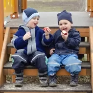 Zwei Kinder sitzen auf einer Treppe und essen Äpfel