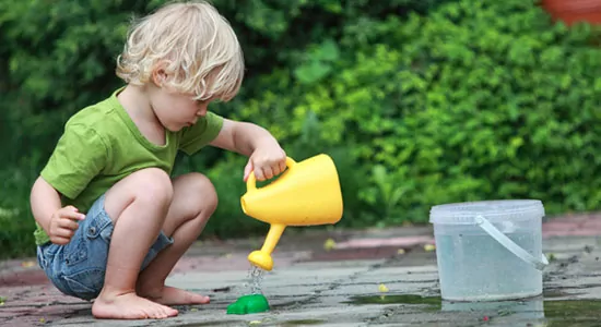 Kleines Kind spielt mit Gießkanne
